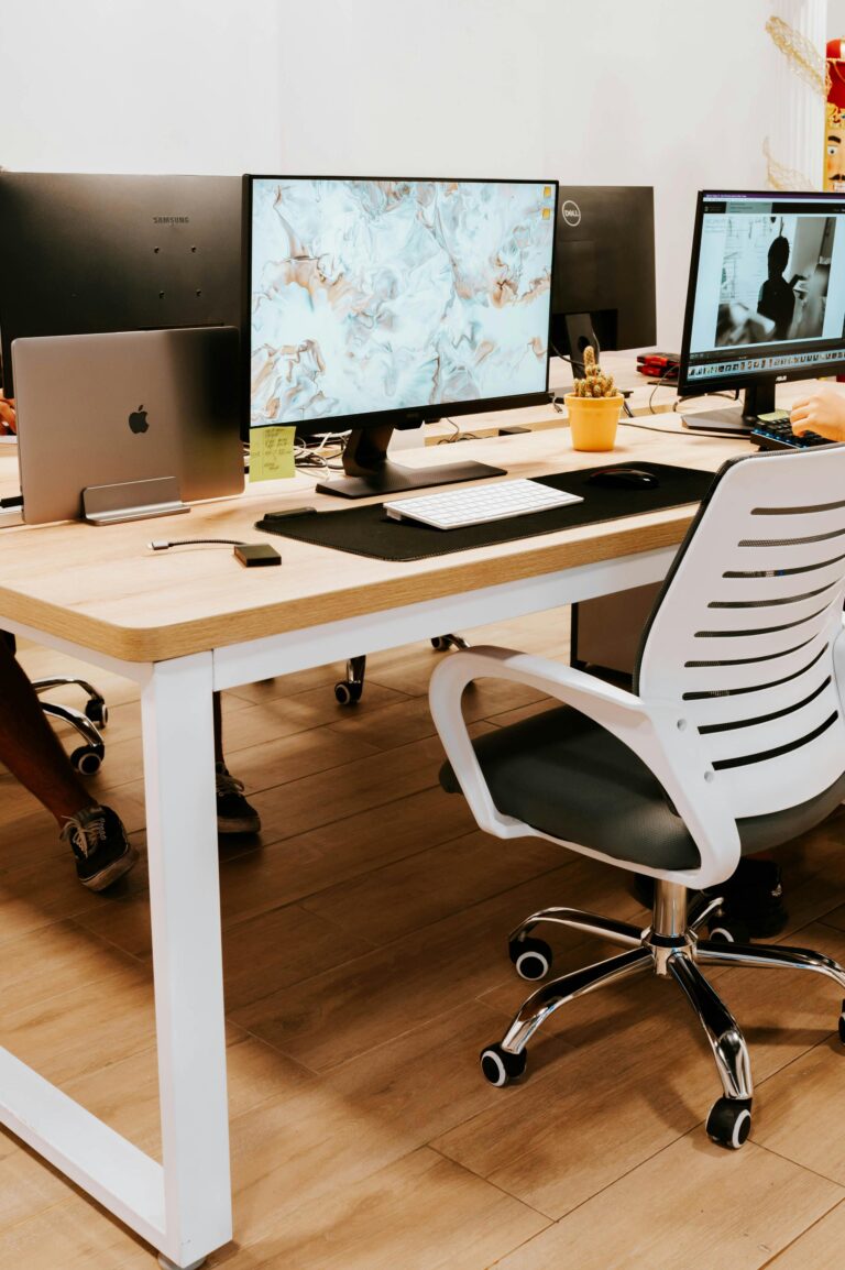 A professionally designed office setup featuring computers, monitors, and a stylish chair.