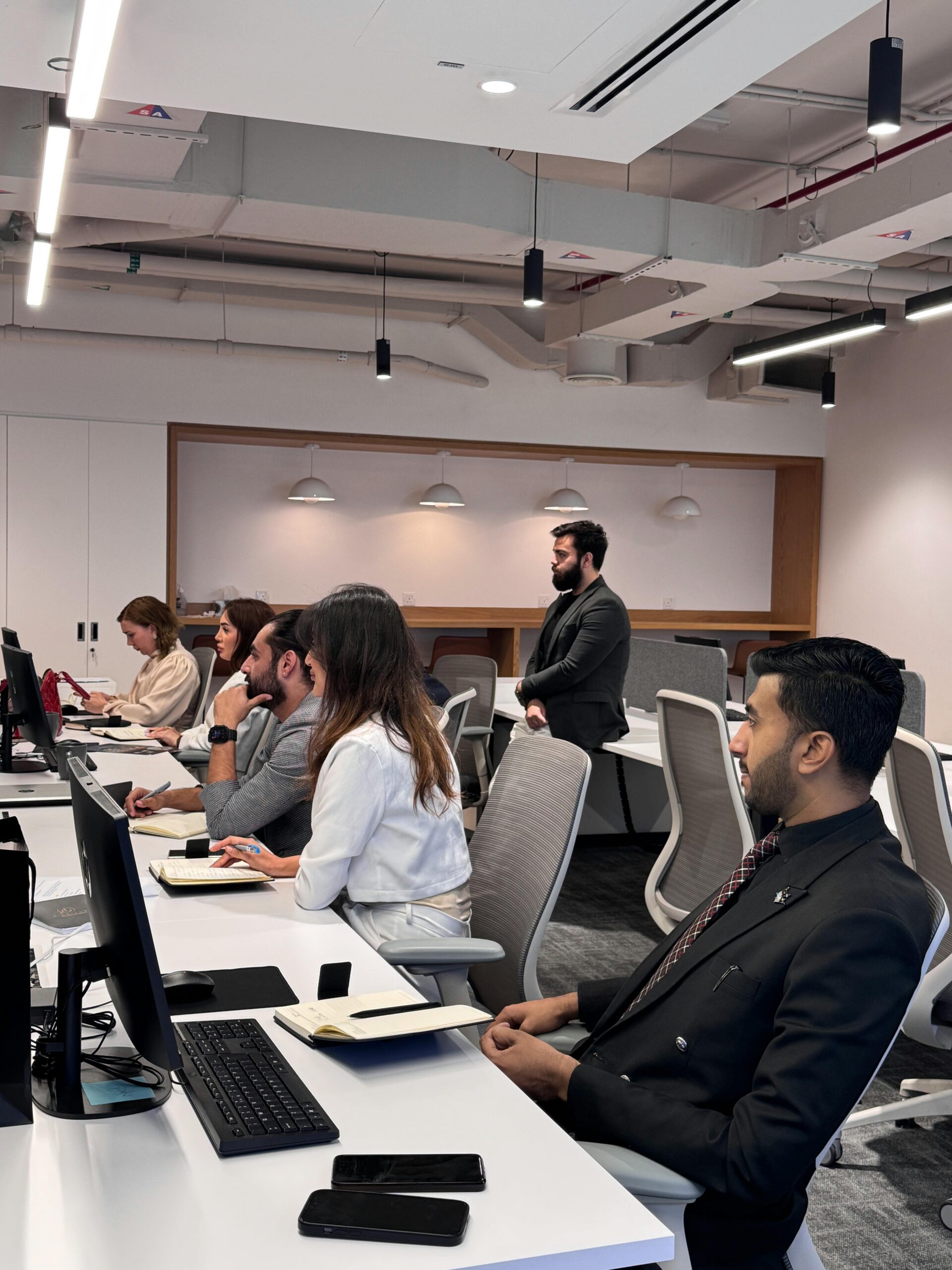 Group of professionals in a modern office collaborating at computer desks.